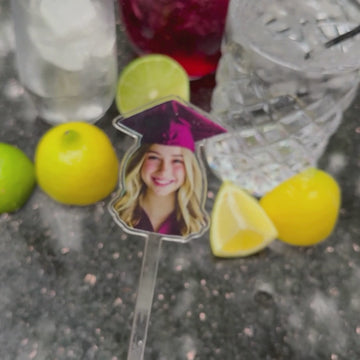 graduate's face on stir stick being placed in drink